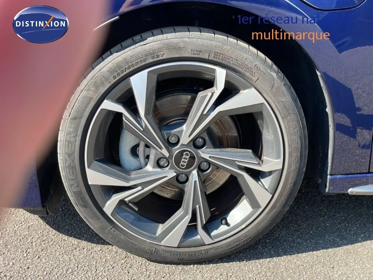 Gros plan sur la roue avant droite d'une Audi A3 Sportback bleu Navarre métal, avec jante alliage au design moderne.