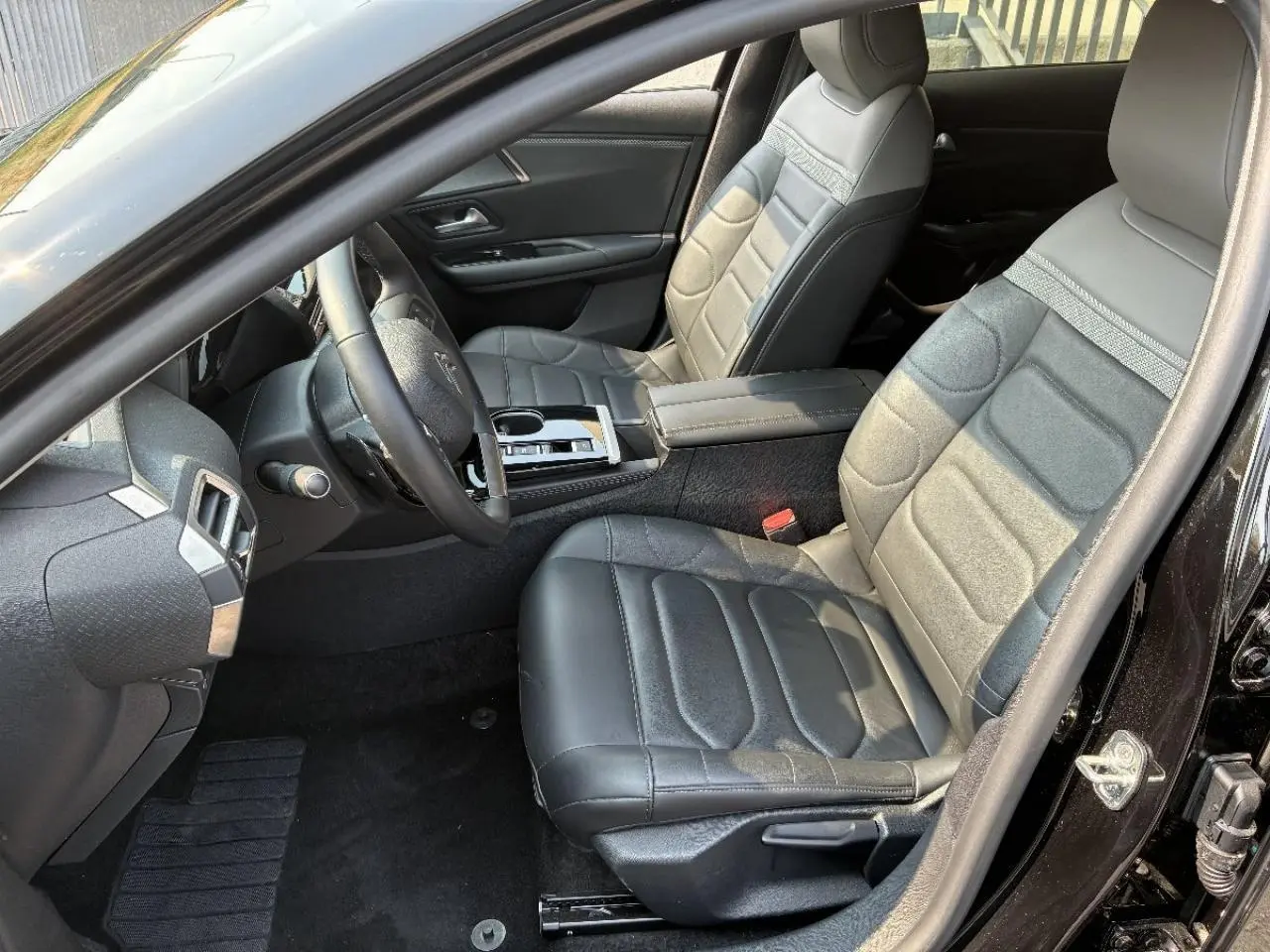 Vue intérieure côté conducteur de la Citroën C5 X 2024 noir perla, mettant en valeur les sièges cuir et la console centrale moderne.