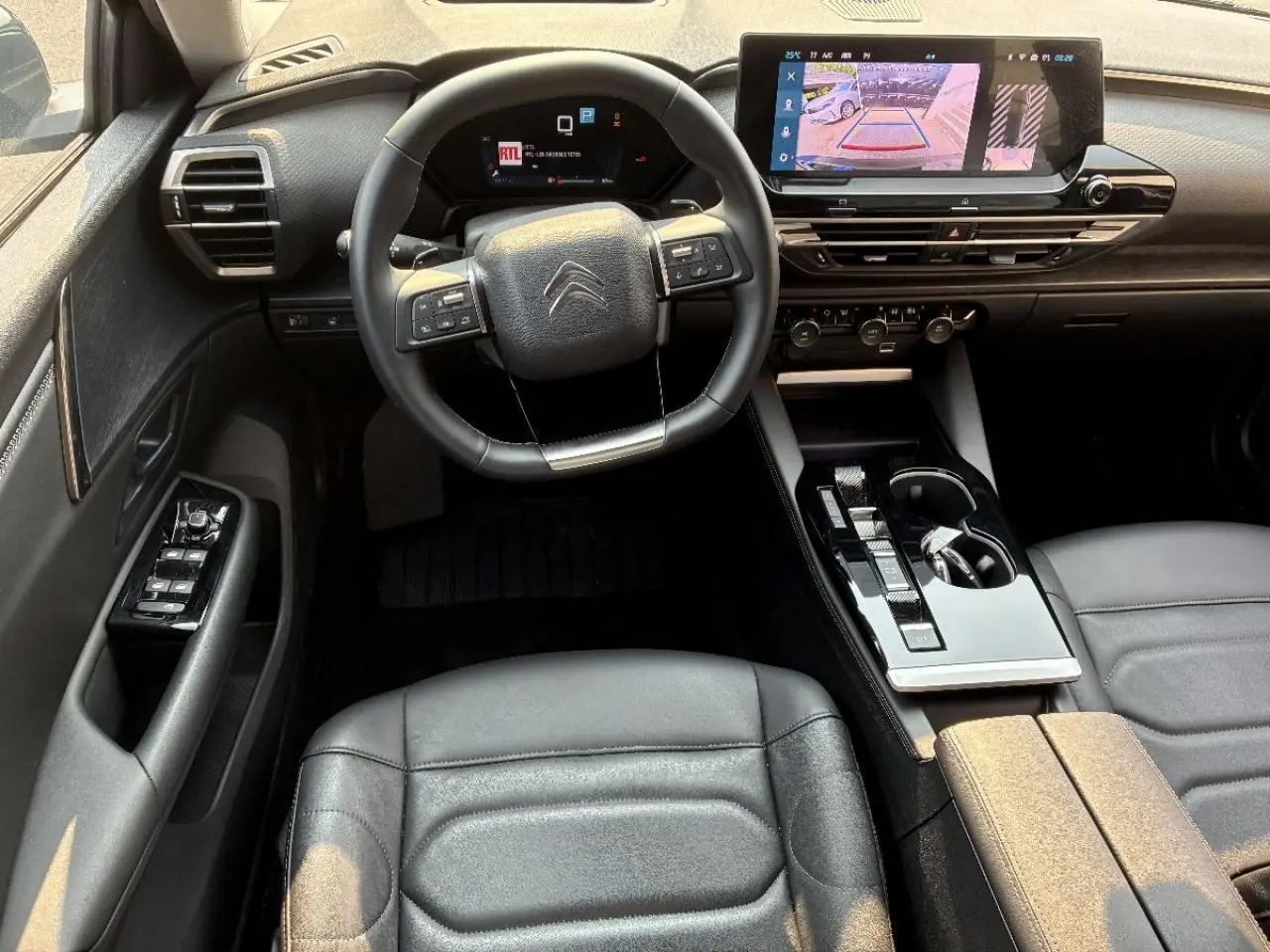 Intérieur noir du Citroën C5 X 2024, vue du poste de conduite avec volant multifonction et écran tactile central.