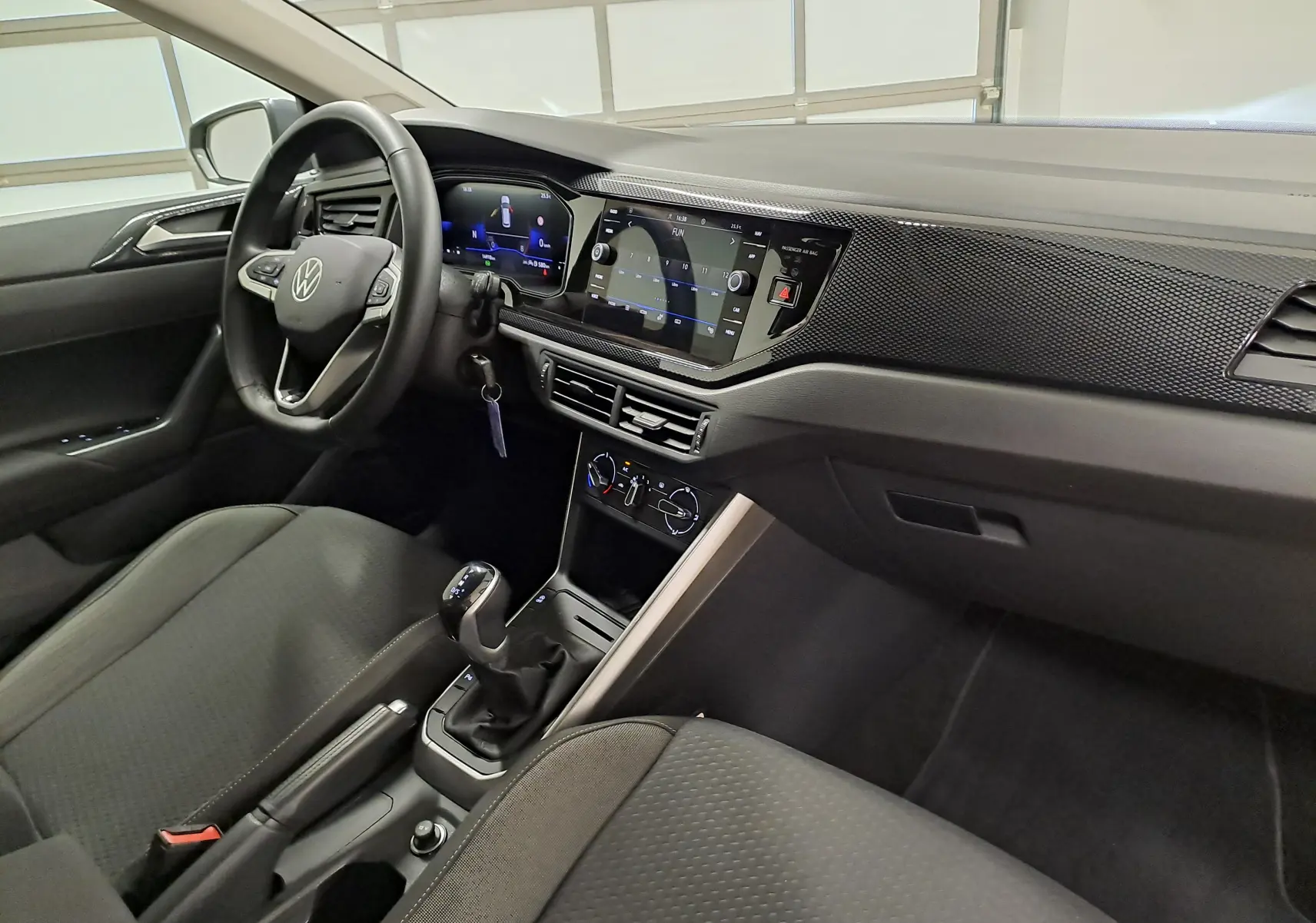 Vue intérieure côté conducteur de la Volkswagen Polo gris cendre 2025, avec tableau de bord digital et console centrale moderne.