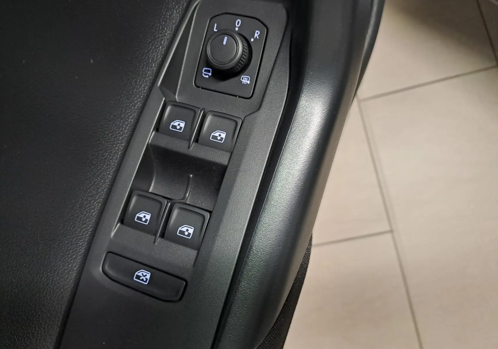 Gros plan sur les commandes de lève-vitres et rétroviseurs côté conducteur du Volkswagen Polo gris cendre 2025.