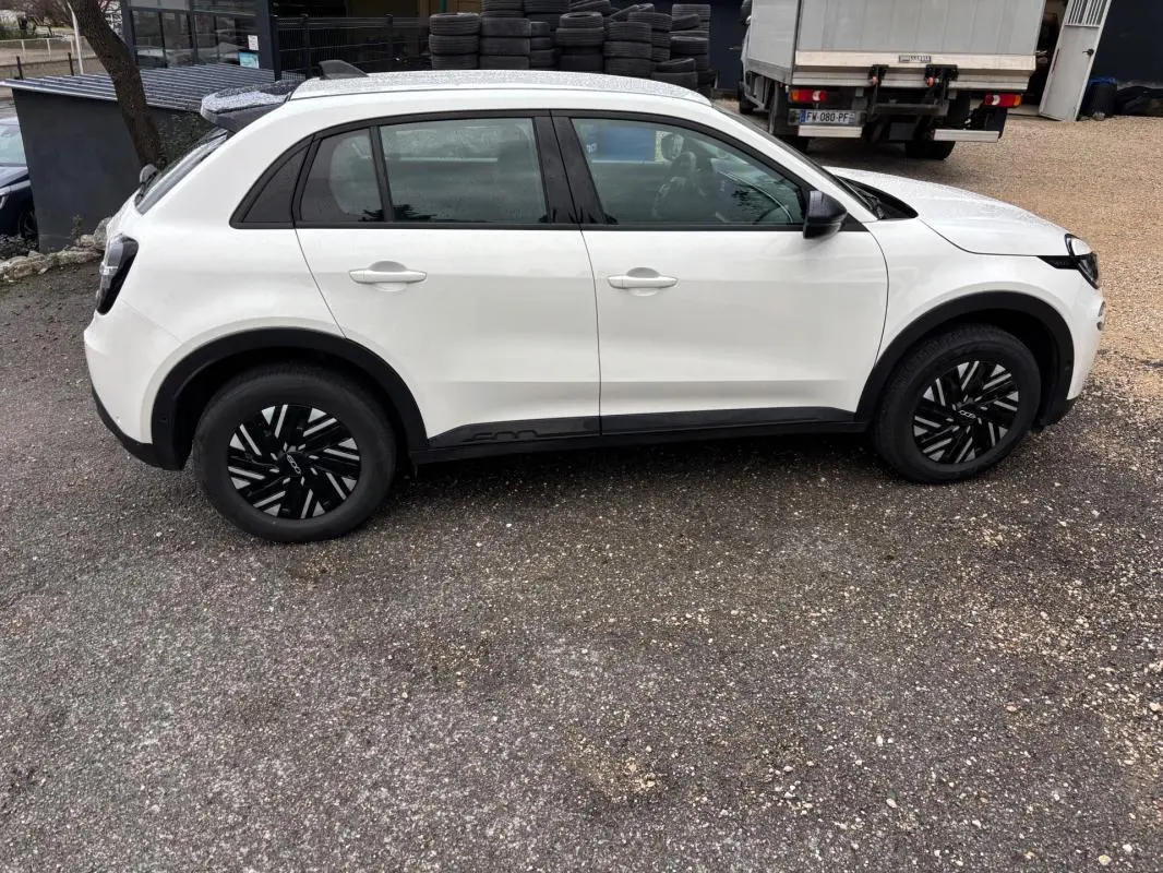Vue de profil côté gauche d'une FIAT 600 blanche 2024 avec jantes noires et détails noirs sur les bas de caisse.