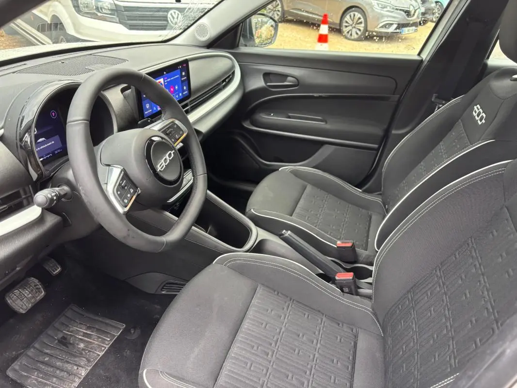Vue intérieure côté conducteur de la FIAT 600 Hybrid 2024 avec sièges noirs et tableau de bord moderne.