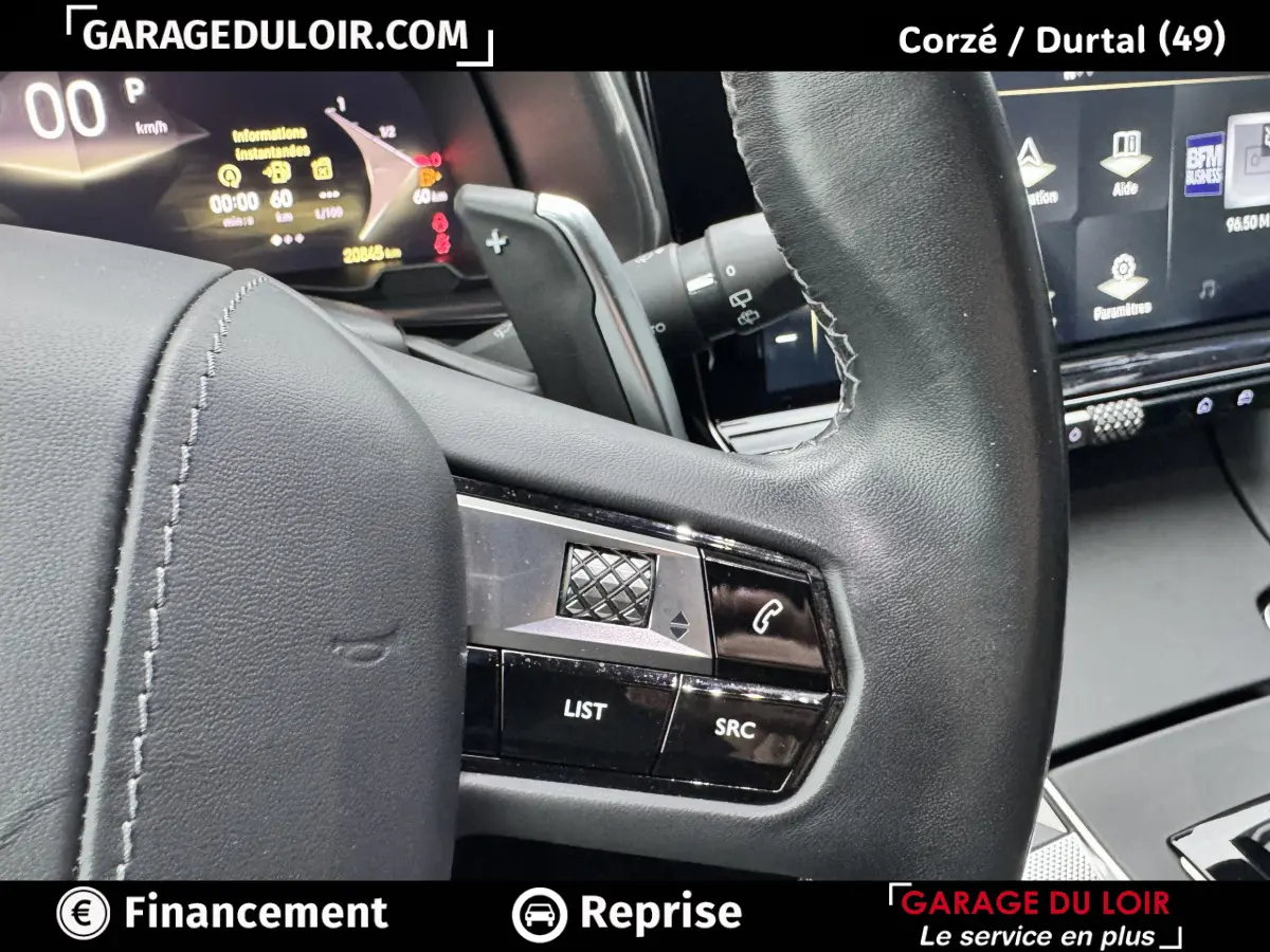 Gros plan sur le volant cuir noir du DS7 Crossback Bleu, avec commandes intégrées et tableau de bord numérique en arrière-plan.