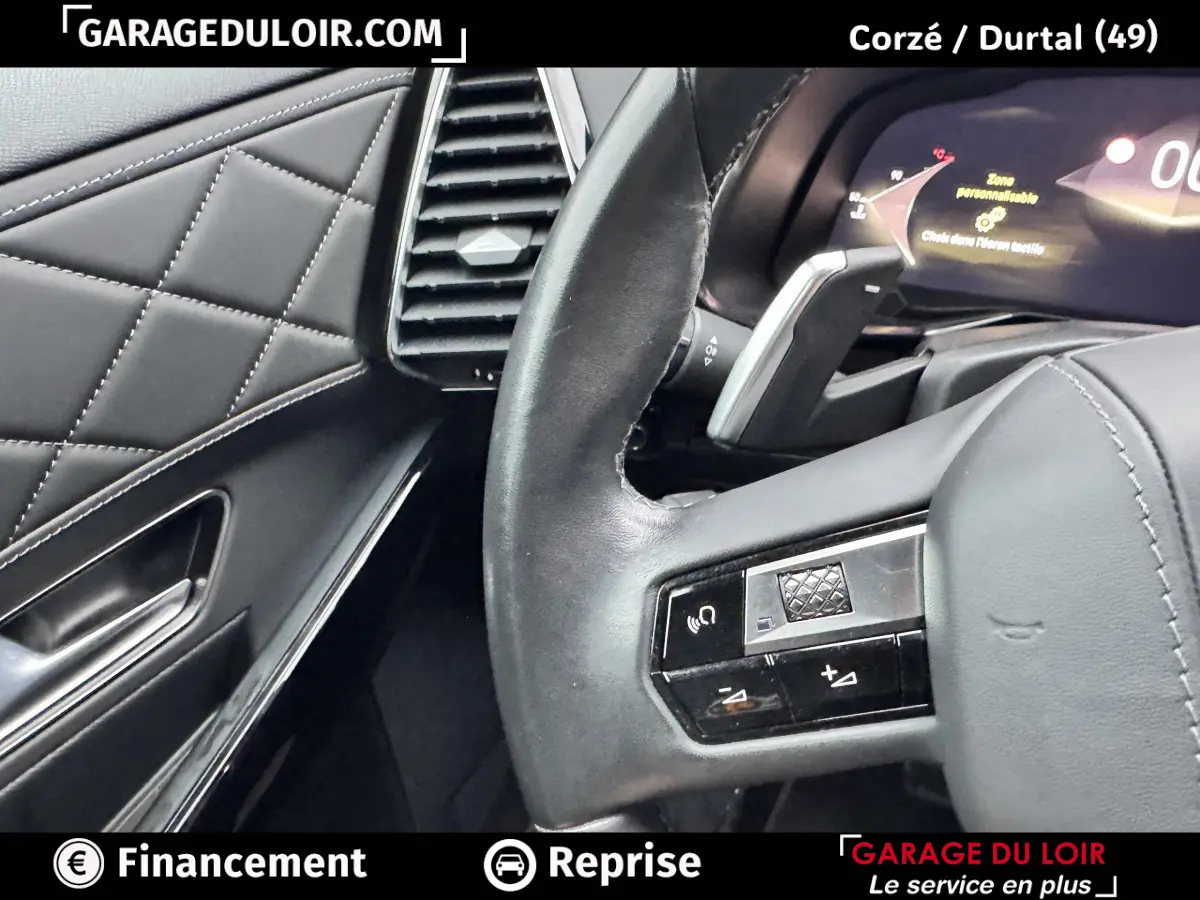 Gros plan sur le volant en cuir noir et partie gauche du tableau de bord matelassé du DS7 Crossback bleu 2024.