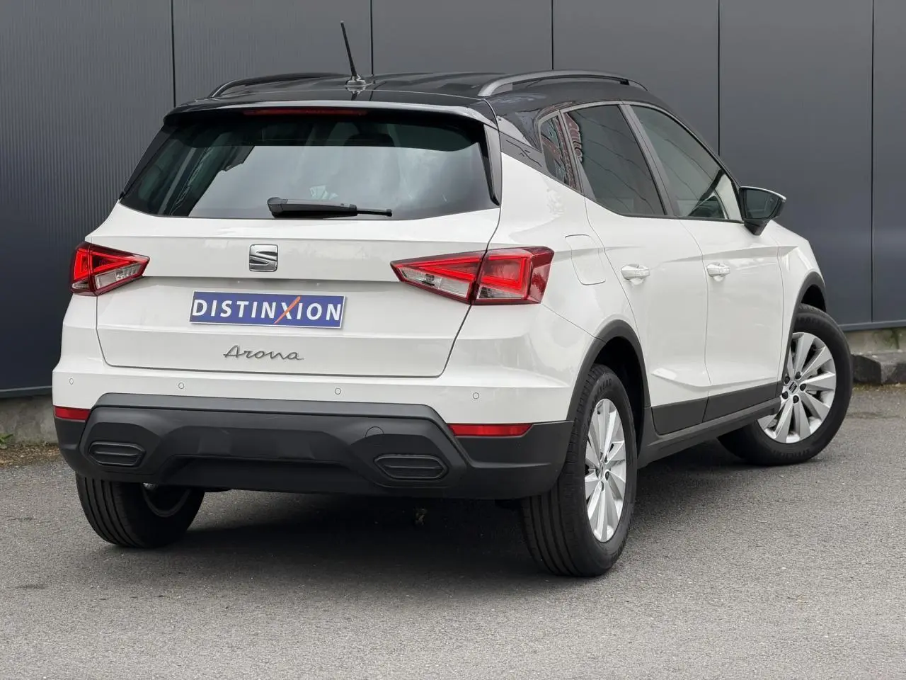 Vue 3/4 arrière droite d'un SEAT Arona blanc avec toit noir contrasté et jantes alliage 16 pouces.
