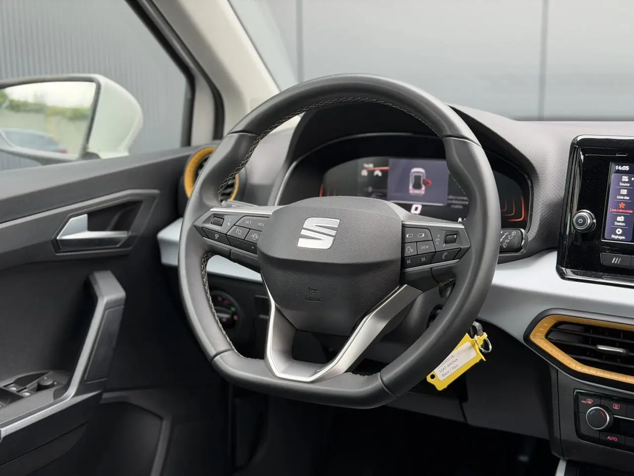 Vue intérieure centrée sur le volant noir du SEAT Arona 2025 avec détails jaunes autour des aérateurs.