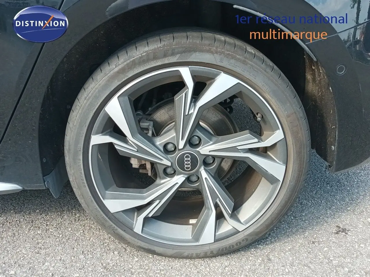 Gros plan sur la roue avant droite de l'Audi A3 Sportback noire, mettant en valeur la jante alliage au design moderne.