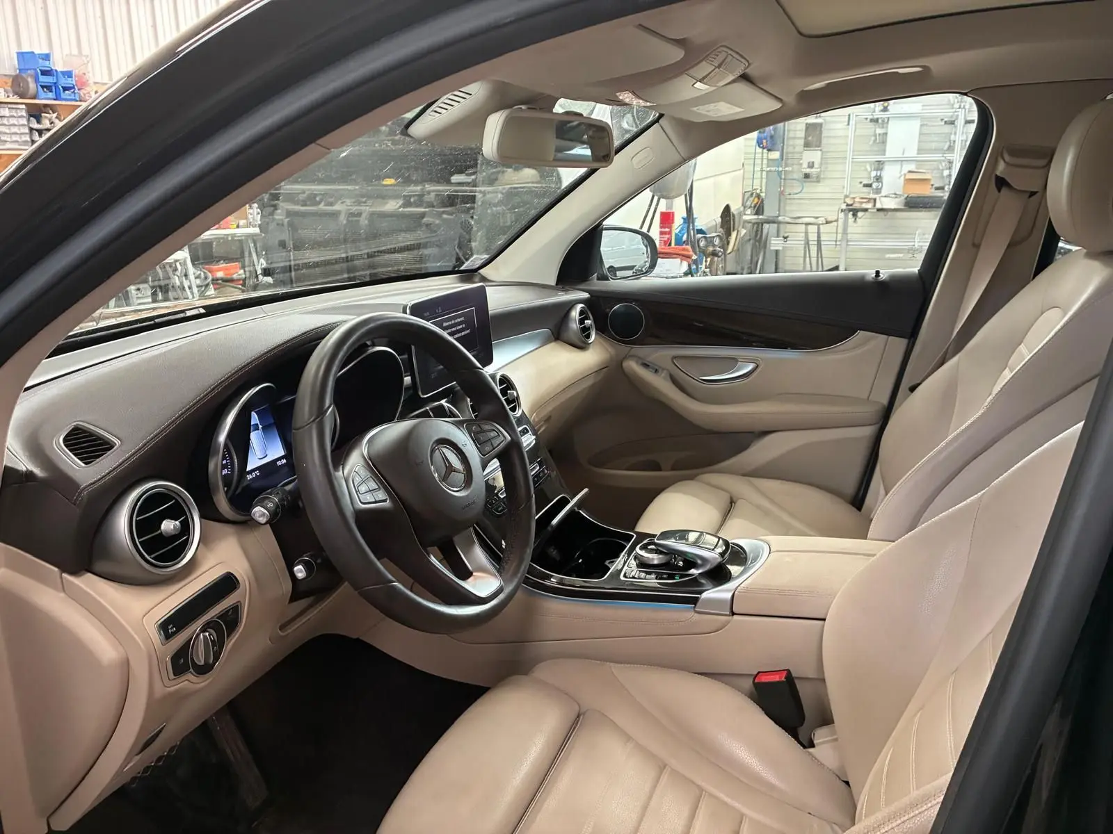 Vue intérieure côté conducteur d’un Mercedes GLC 220D Fascination 2017 avec sellerie cuir beige et tableau de bord noir.