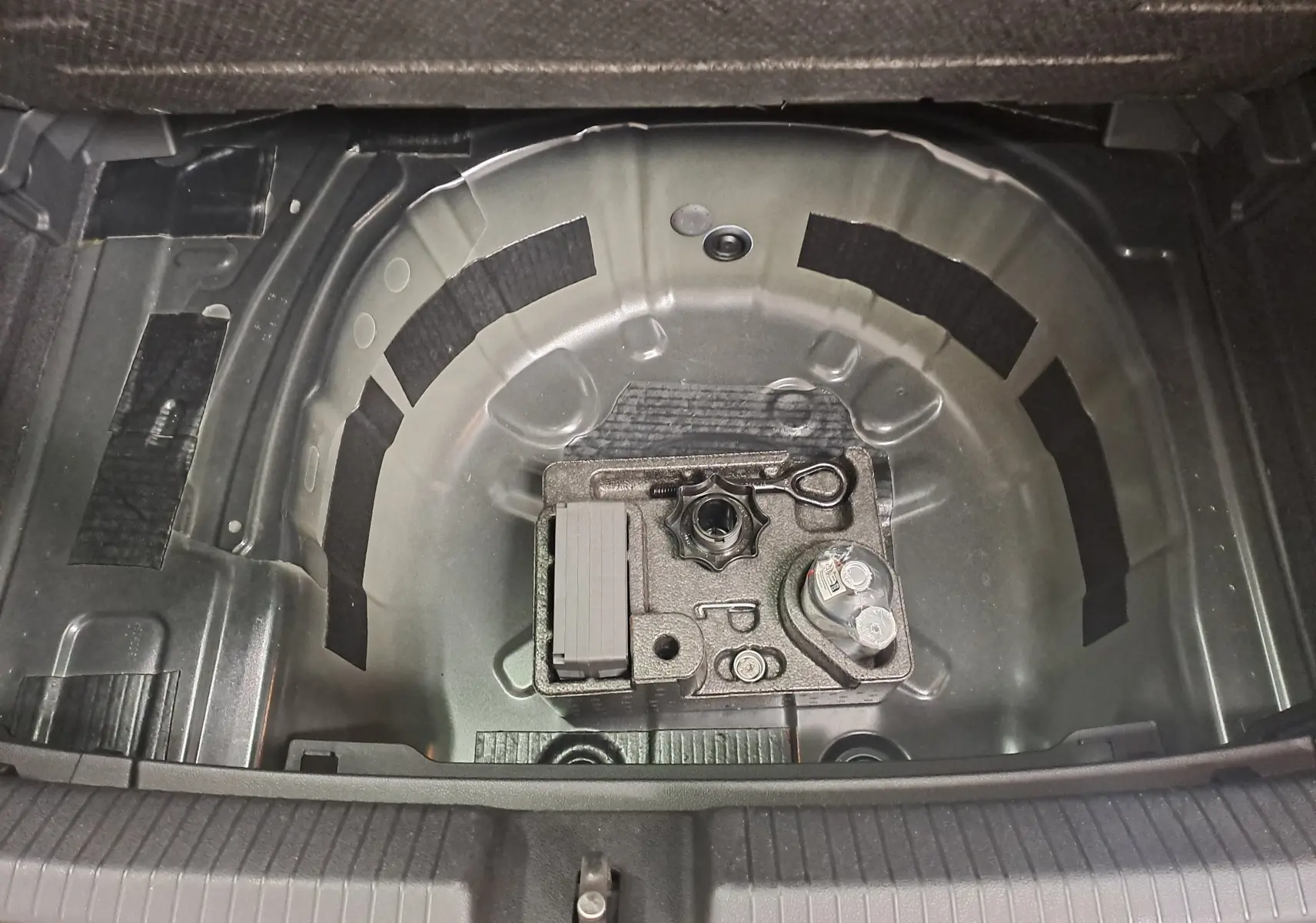 Coffre ouvert de Volkswagen Polo 2025 noir intense, vue plongeante sur le rangement sous plancher sans roue de secours.