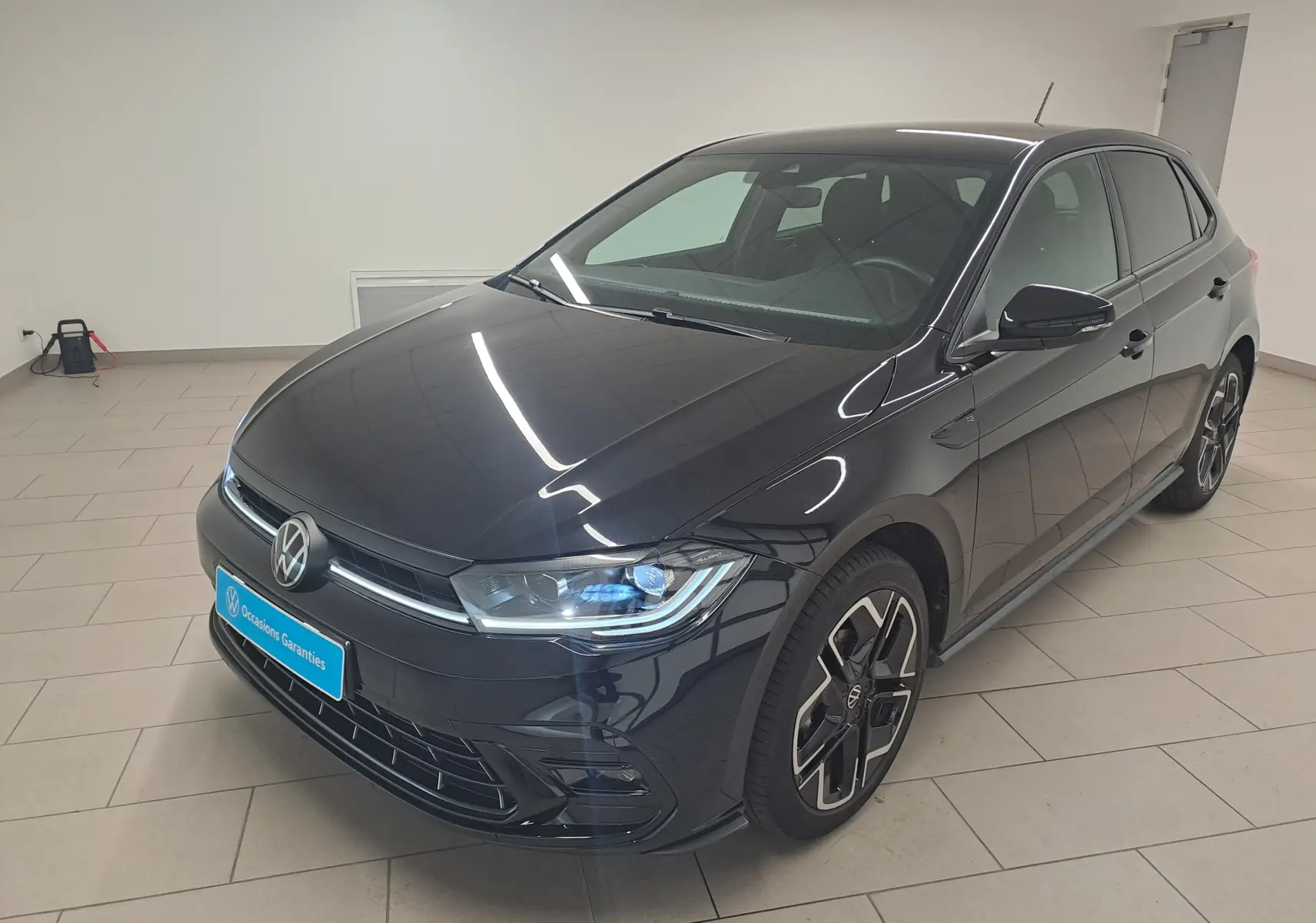 Volkswagen Polo 1.0 TSI R-Line noir intense vue 3/4 avant droit en intérieur, jantes spécifiques R-Line visibles.