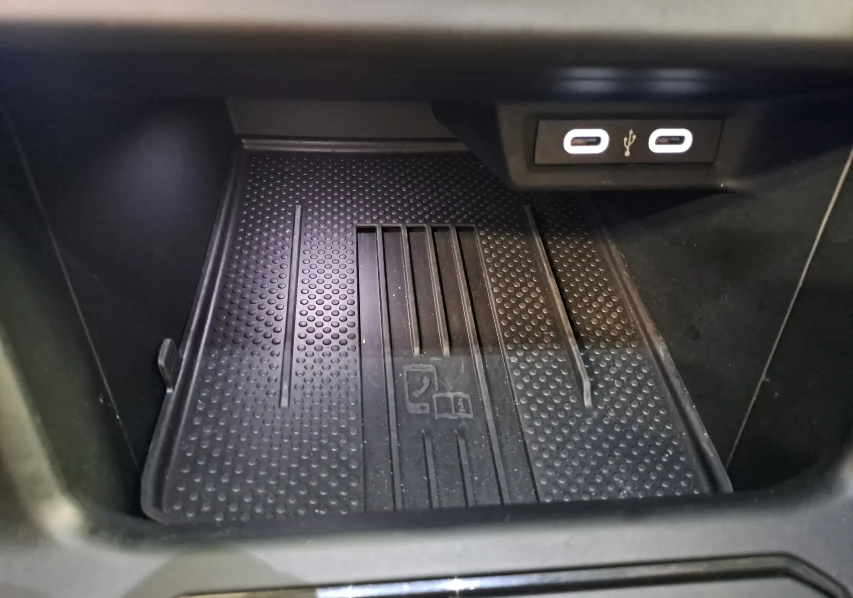 Gros plan sur le compartiment de rangement intérieur avec deux ports USB-C lumineux dans une Volkswagen Polo Noir Intense.