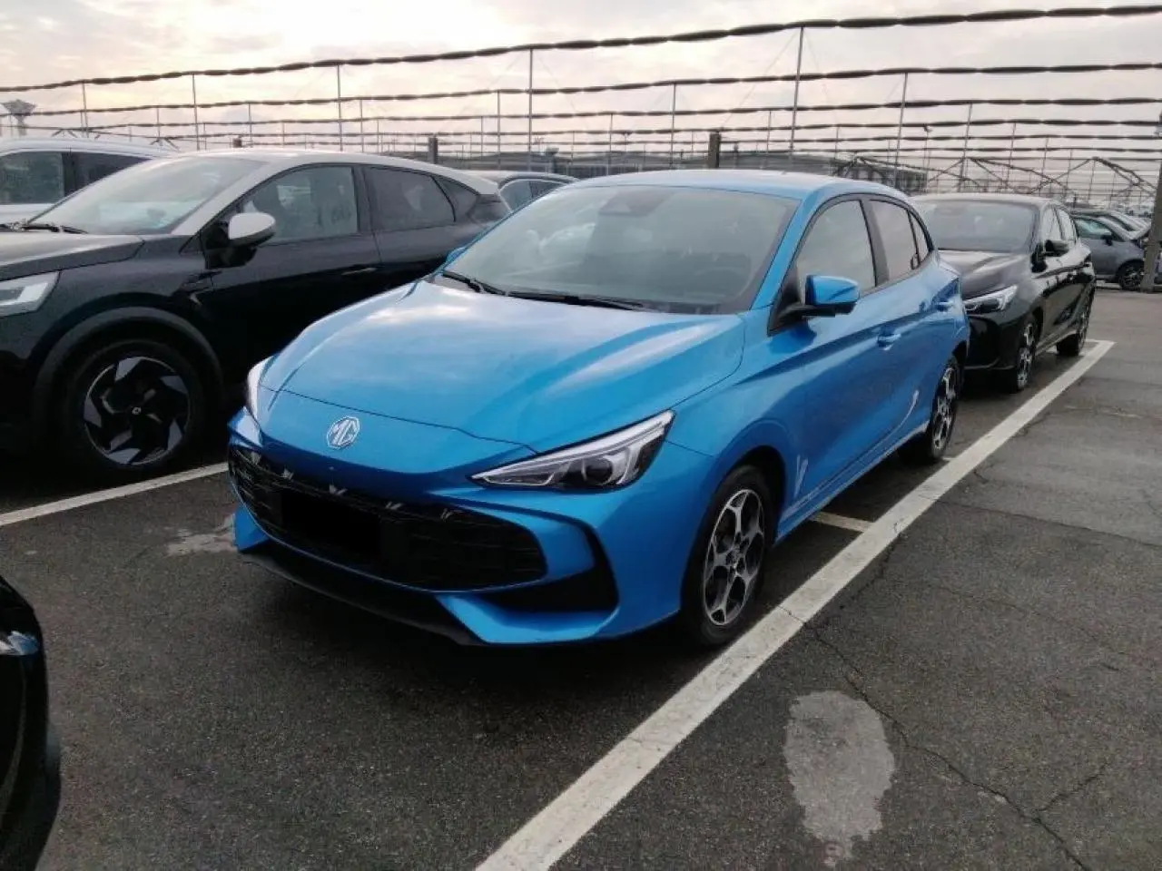 Vue 3/4 avant gauche d'une MG3 1.5 Hybrid+ 195 Luxury bleu Como avec jantes alliage et calandre noire.