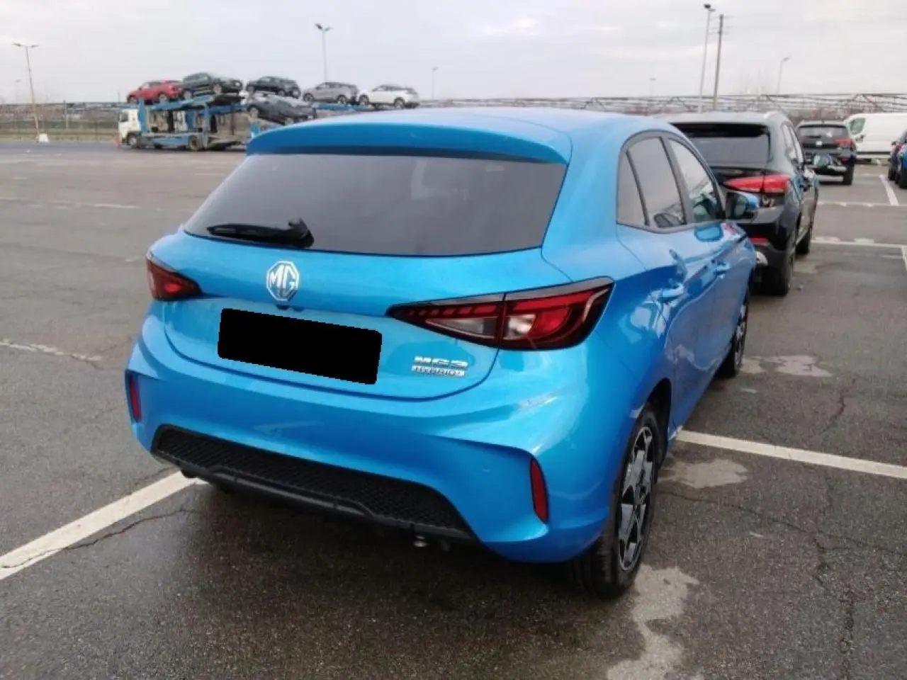 Vue 3/4 arrière droite d'une MG3 1.5 Hybrid+ 195 Luxury bleu Como avec vitres arrière surteintées sur parking.