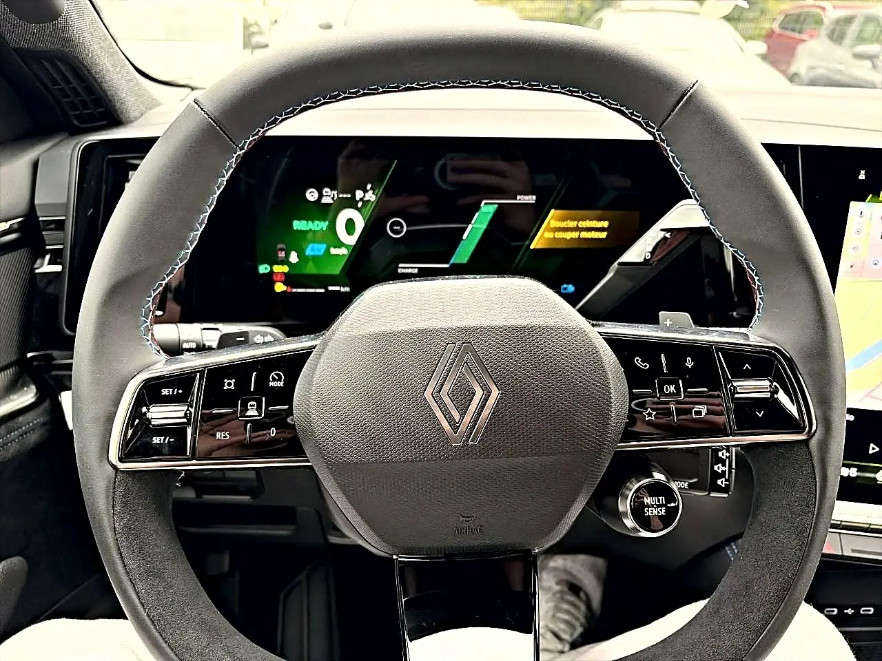 Vue frontale du volant noir du Renault Austral 2026 avec commandes multifonctions et écran numérique en arrière-plan.