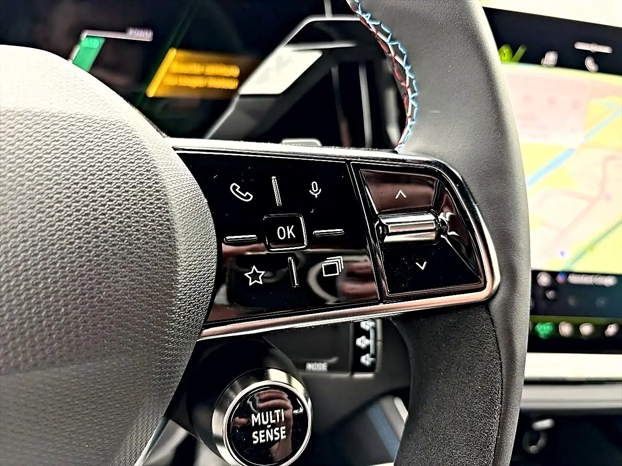 Gros plan sur le côté droit du volant du Renault Austral gris schiste, avec commandes multifonctions et écran tactile en arrière-plan.