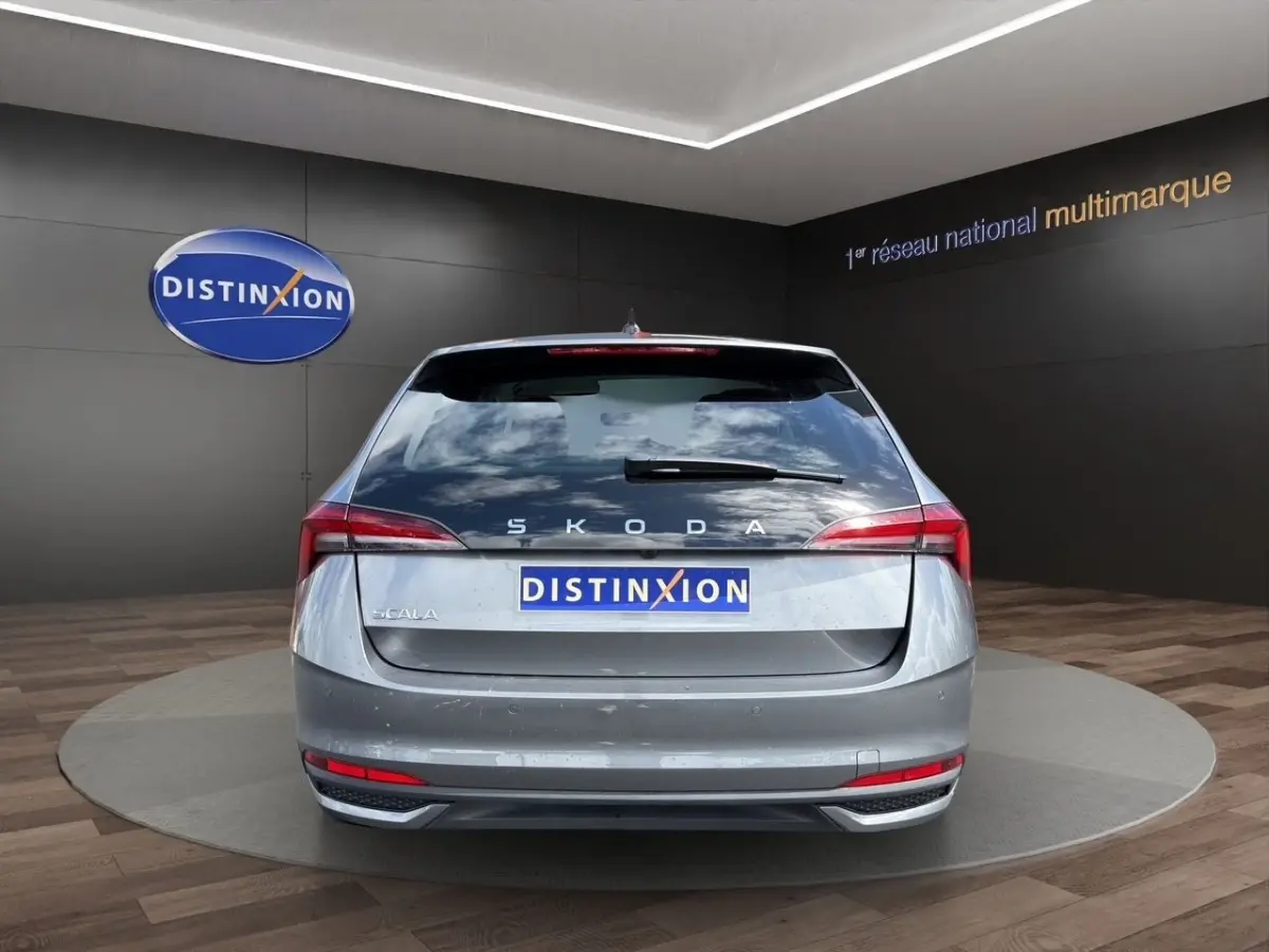 Vue arrière d'une Skoda Scala gris foncé exposée en showroom avec logo Distinxion en arrière-plan.