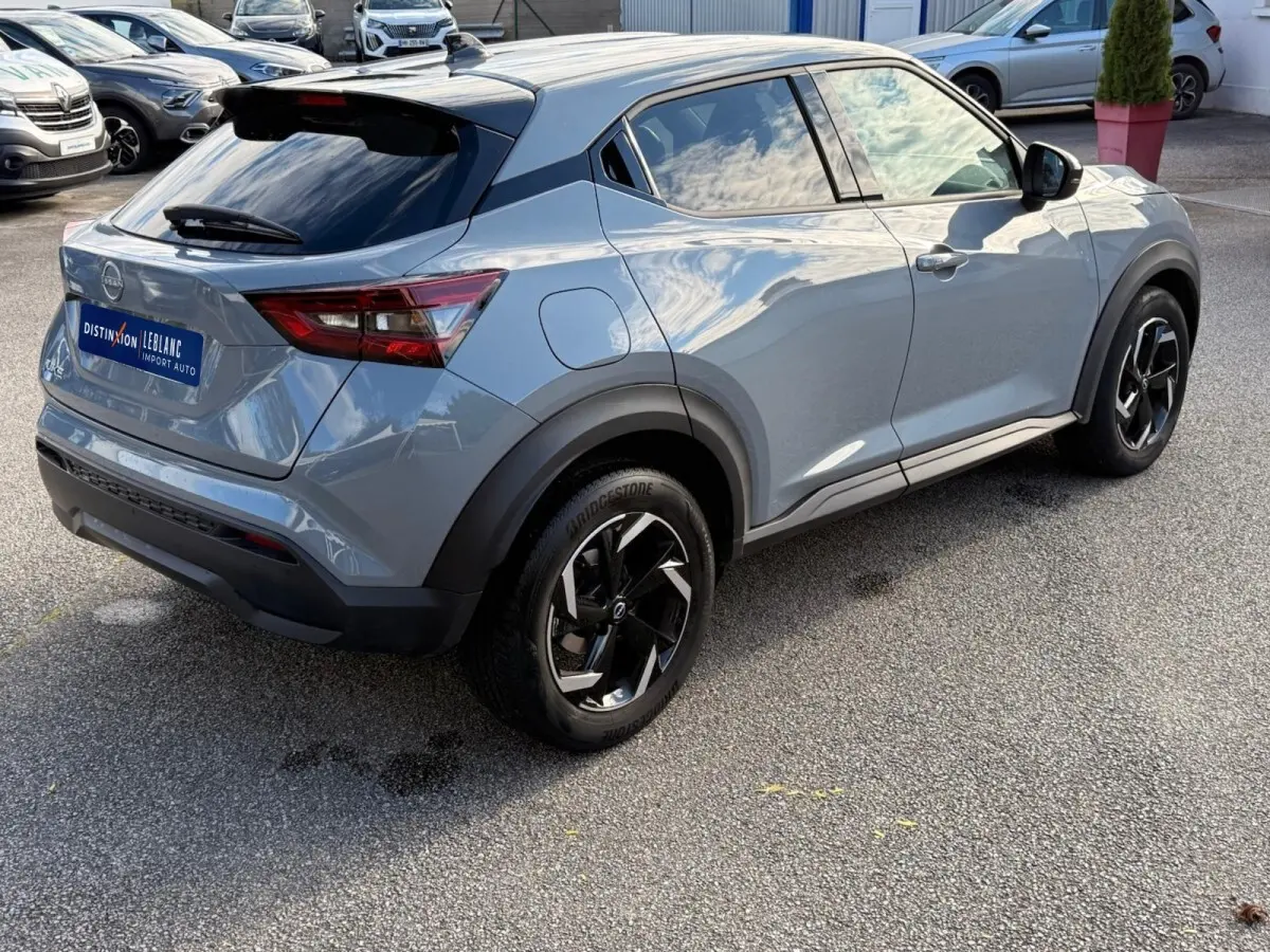 Nissan Juke gris clair vu en 3/4 arrière droit, avec jantes noires et détails noirs contrastants.