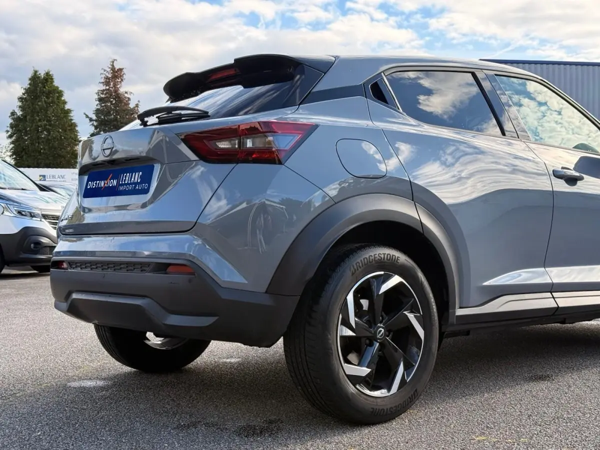 Vue 3/4 arrière droite du Nissan Juke gris clair 2023 avec jantes noires et feux arrière LED distinctifs.