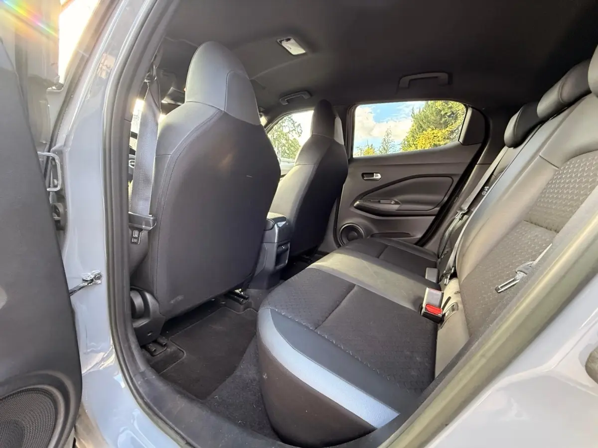 Vue intérieure arrière côté droit du Nissan Juke gris clair 2023, montrant la banquette 3 places et les dossiers des sièges avant.