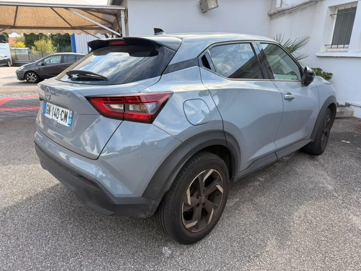 Nissan Juke gris clair vu de profil côté gauche, avec jantes noires et toit noir contrastant.