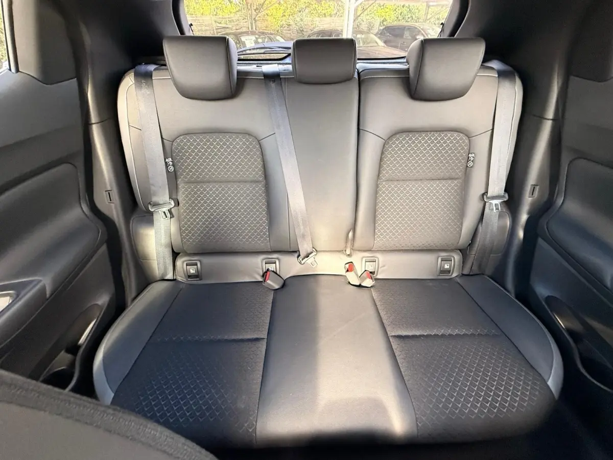 Vue intérieure sur la banquette arrière noire du Nissan Juke 2023, avec ceintures de sécurité et appuie-têtes visibles.
