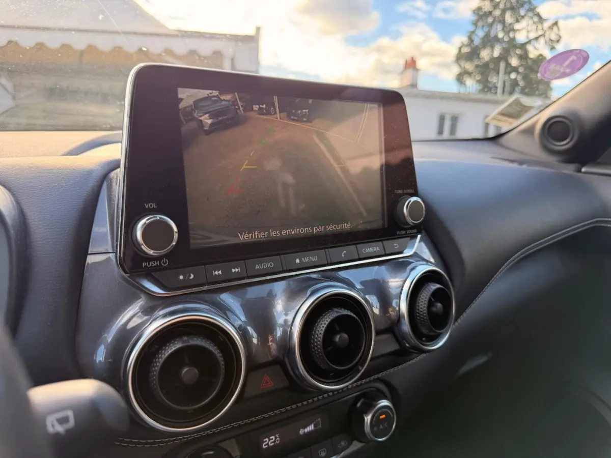 Vue intérieure du tableau de bord du Nissan Juke gris clair 2023, avec écran tactile affichant la caméra de recul.