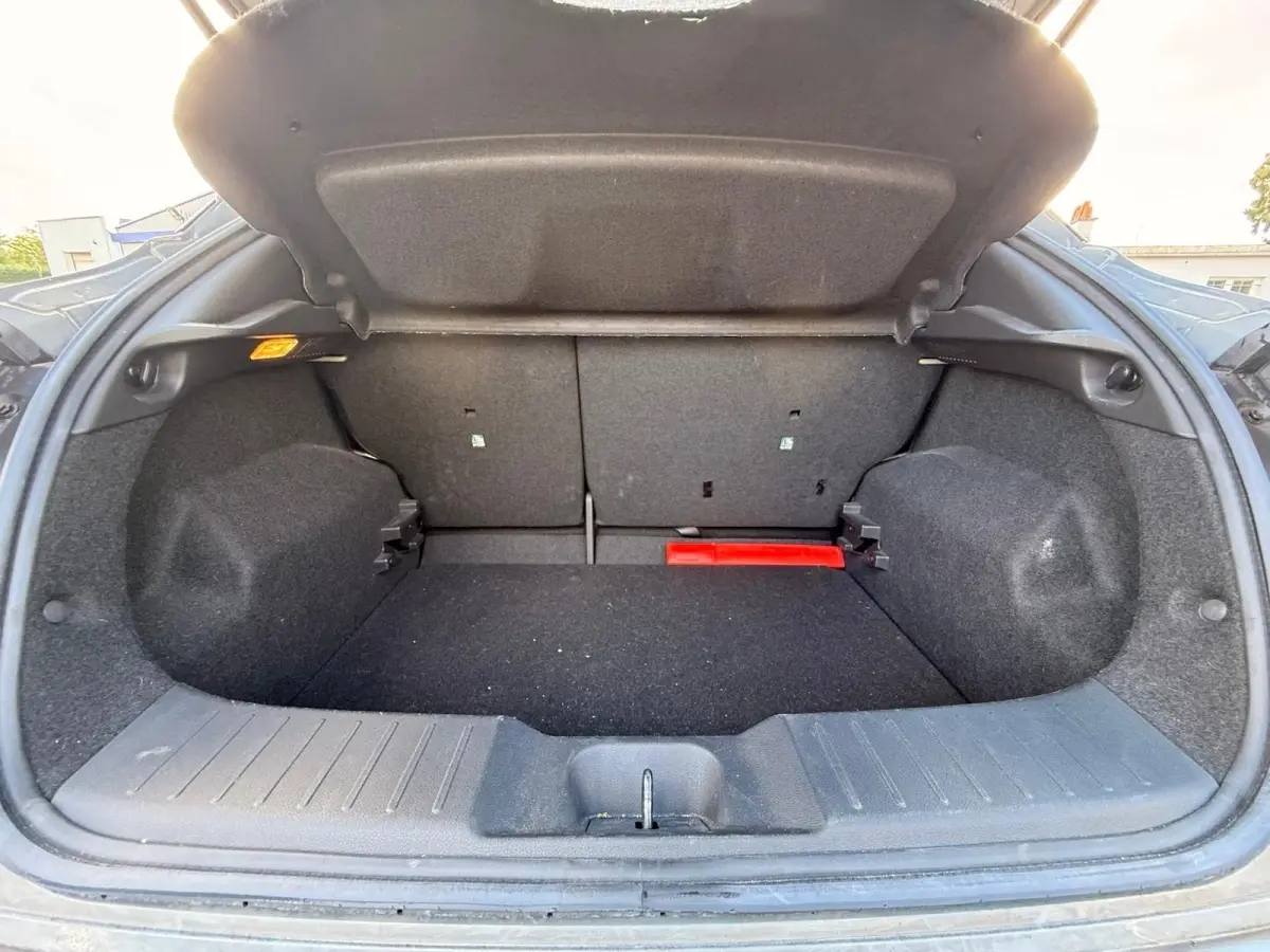 Coffre ouvert de Nissan Juke gris clair 2023, vue de l’arrière montrant l’espace de chargement et la banquette rabattable.