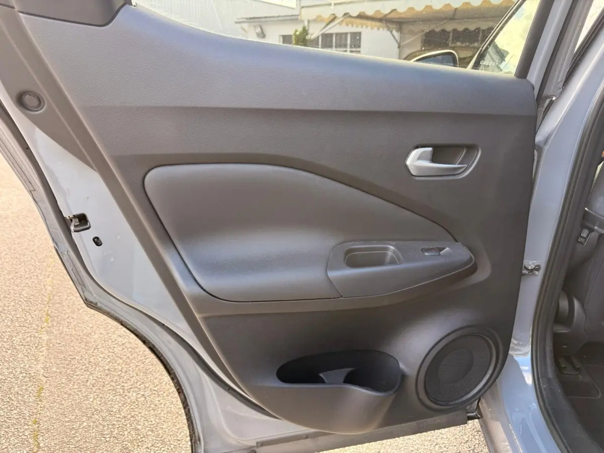 Vue rapprochée de la porte arrière gauche gris clair du Nissan Juke 2023 avec poignée et haut-parleur intégrés.