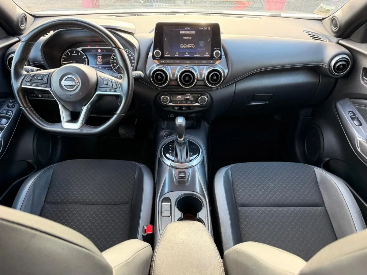 Vue intérieure avant du Nissan Juke 2023 avec tableau de bord noir, écran tactile central et volant cuir multifonctions.