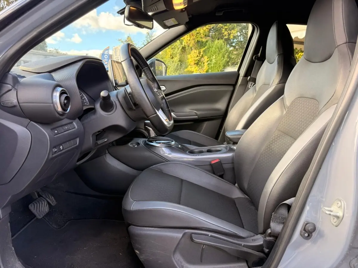 Vue intérieure côté conducteur du Nissan Juke gris clair 2023, mettant en valeur les sièges et le tableau de bord.