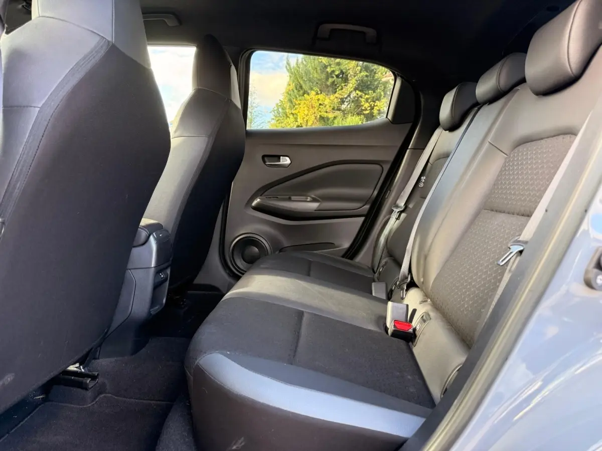Vue intérieure côté droit sur la banquette arrière noire du Nissan Juke gris clair 2023, avec ceinture de sécurité visible.