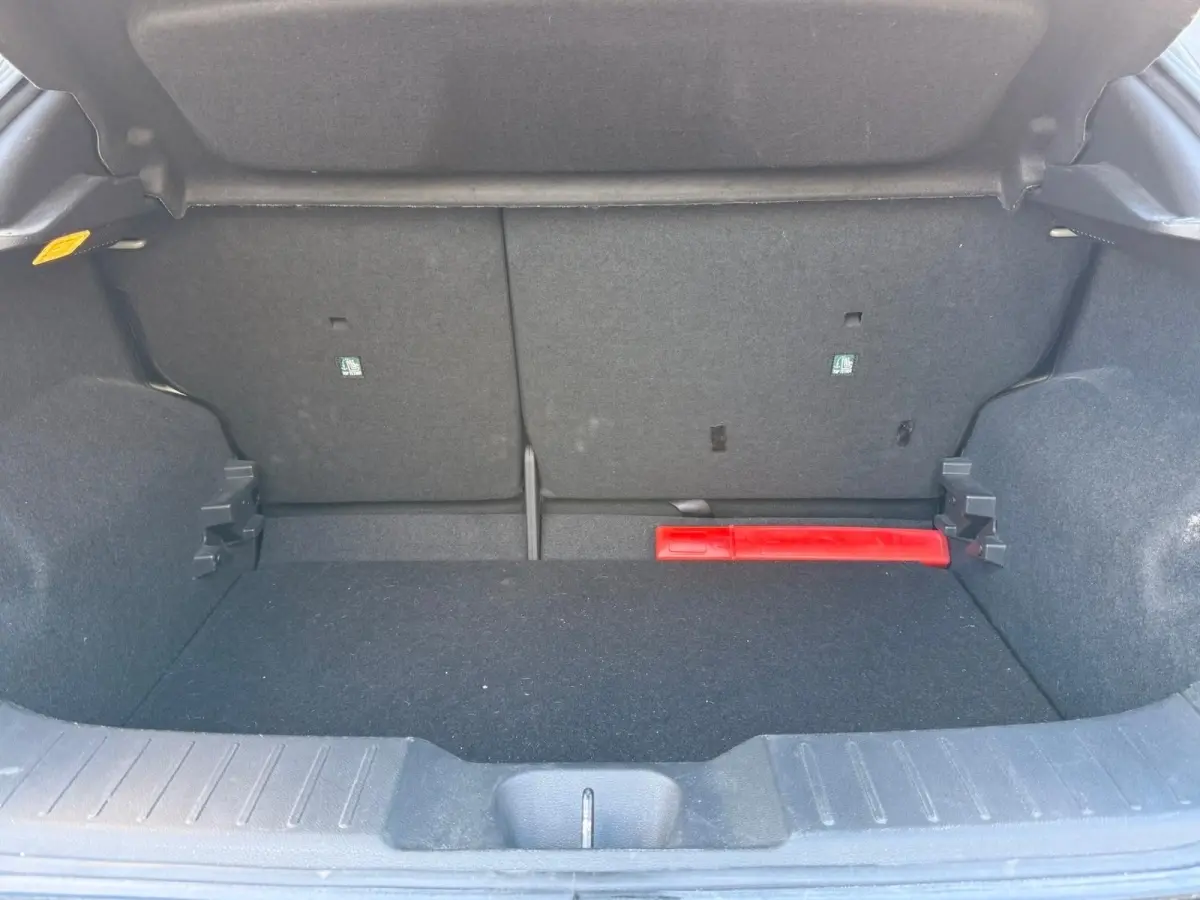 Coffre ouvert du Nissan Juke gris clair 2023, vue intérieure montrant un espace de rangement avec un triangle de signalisation rouge.
