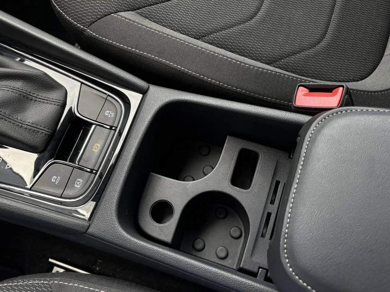 Gros plan sur la console centrale noire du Skoda Kodiaq 2024, montrant le levier de vitesses et les porte-gobelets.