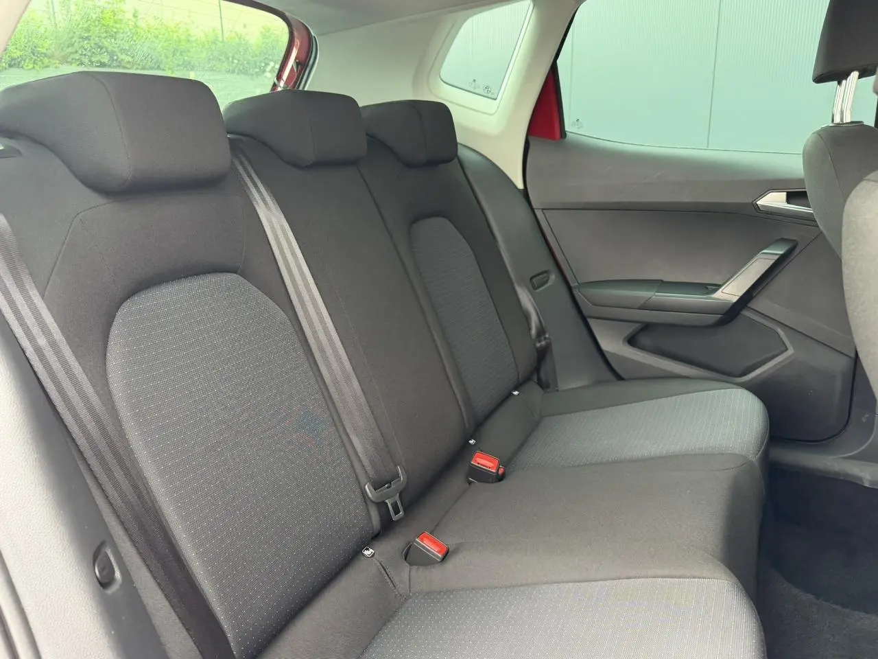 Vue intérieure côté droit des sièges arrière noirs du SEAT Arona Rouge Désir avec ceinture et appuie-têtes visibles.