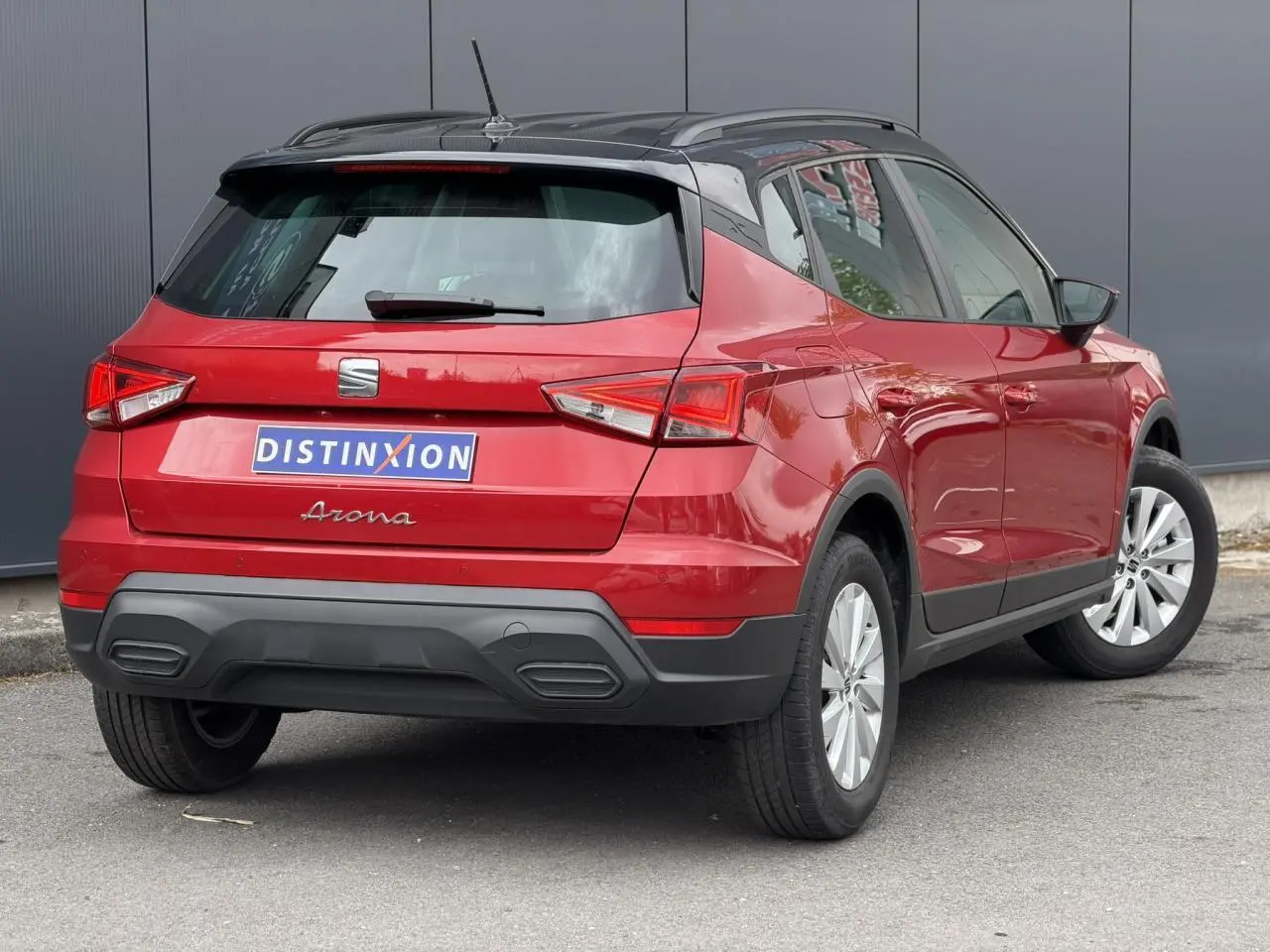 Vue 3/4 arrière droite d’un SEAT Arona rouge Désir avec toit noir et jantes alliage 16 pouces.
