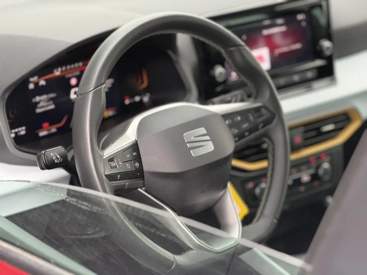Vue rapprochée du volant noir du SEAT Arona TSI 115 Style 2025 avec tableau de bord digital et écran tactile.