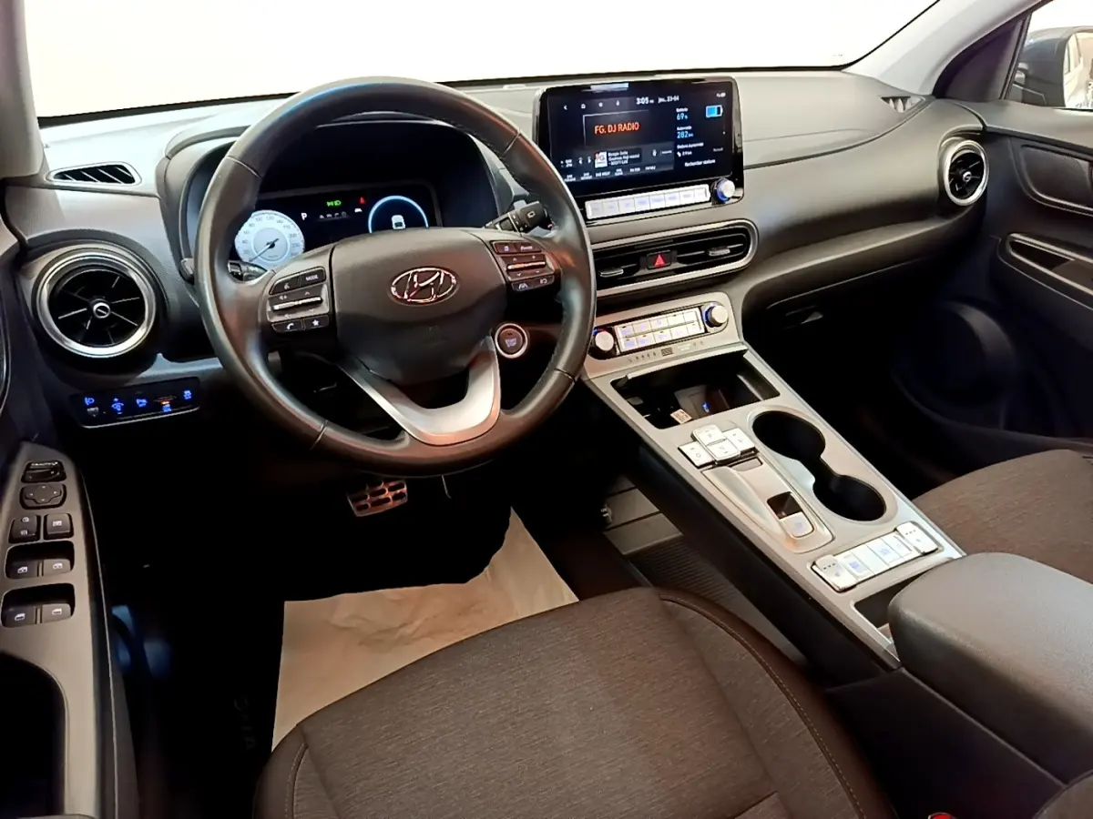 Intérieur de la Hyundai Kona électrique 2023 vu côté conducteur, volant cuir multifonctions et écran tactile central.