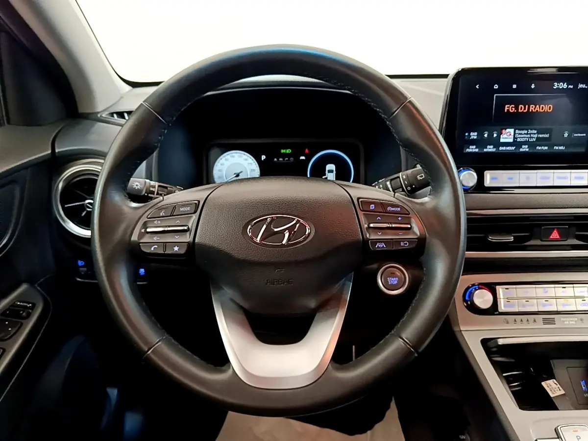 Vue intérieure centrée sur le volant cuir multifonctions noir du Hyundai Kona électrique 2023 avec tableau de bord numérique.