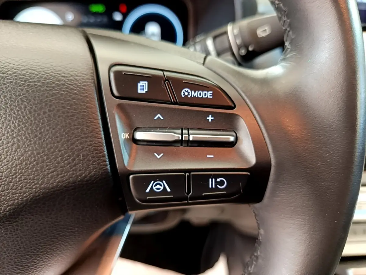 Gros plan sur les commandes multifonctions du volant cuir à droite du Hyundai Kona électrique bleu 2023.