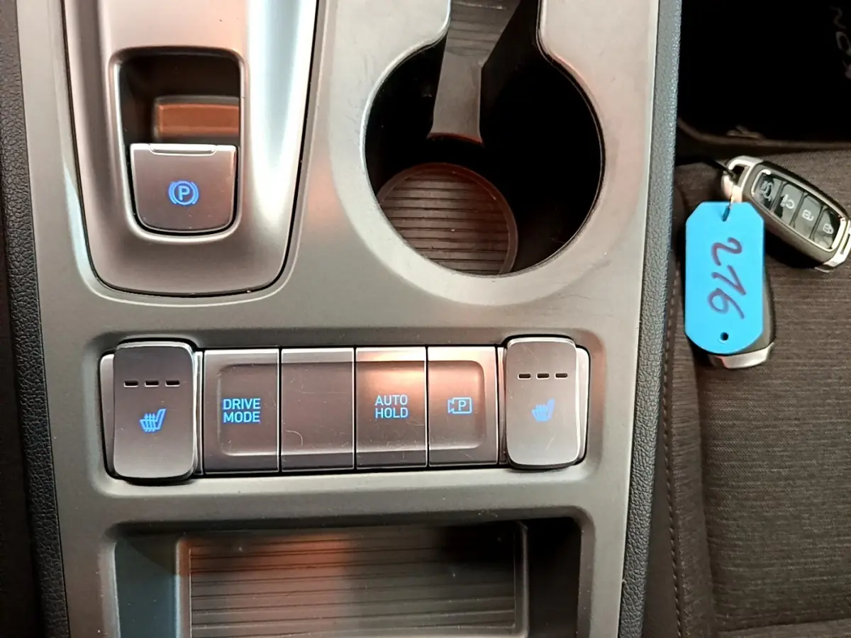 Gros plan sur la console centrale du Hyundai Kona électrique 2023, avec boutons chauffants et mode de conduite.