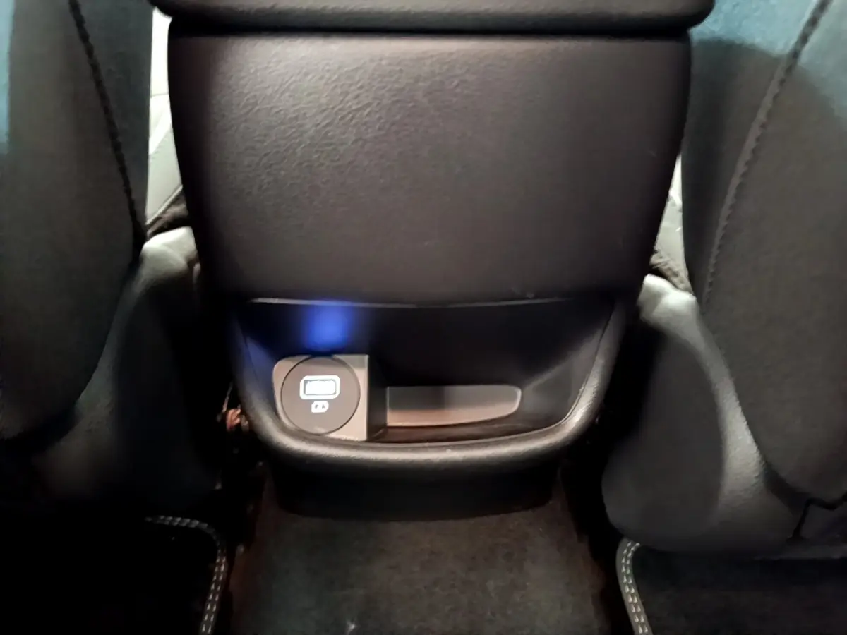 Prise USB arrière noire sous l'accoudoir central du Hyundai Kona électrique bleu 2023, vue rapprochée.