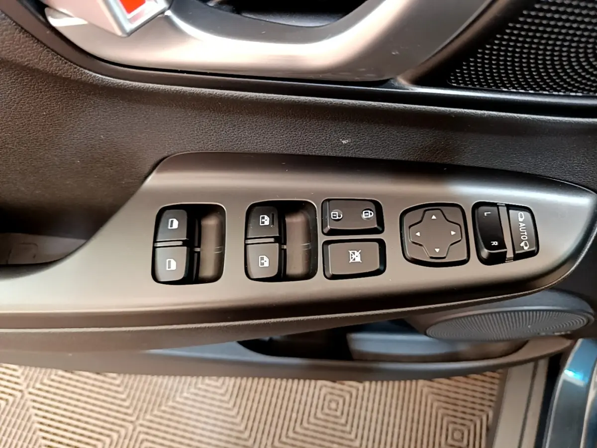Gros plan sur les commandes de porte côté gauche d’un Hyundai Kona bleu, avec boutons de vitres et réglages des rétroviseurs.