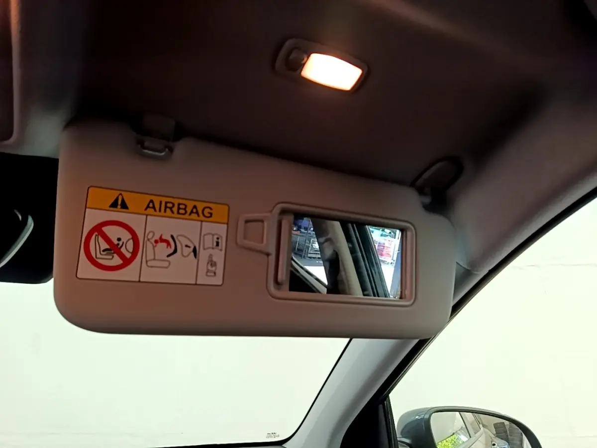 Vue intérieure du pare-soleil côté conducteur avec miroir et avertissement airbag dans un Hyundai Kona bleu 2023.