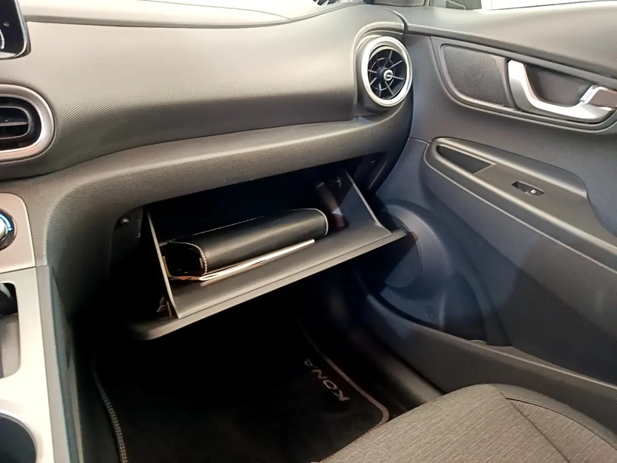 Intérieur côté passager du Hyundai Kona électrique 2023, boîte à gants ouverte avec pochette noire visible.