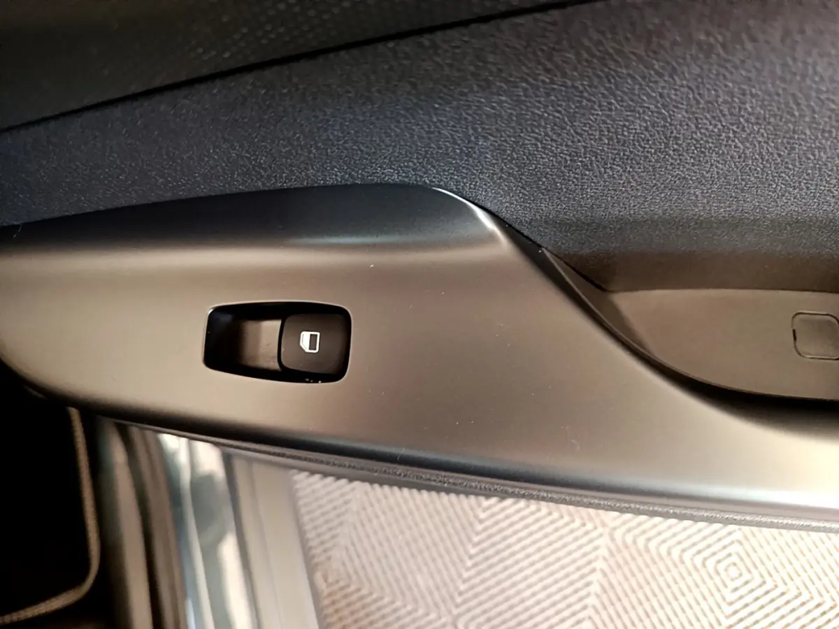 Détail du bouton de commande de la vitre électrique sur la porte intérieure d’une Hyundai Kona bleu électrique.