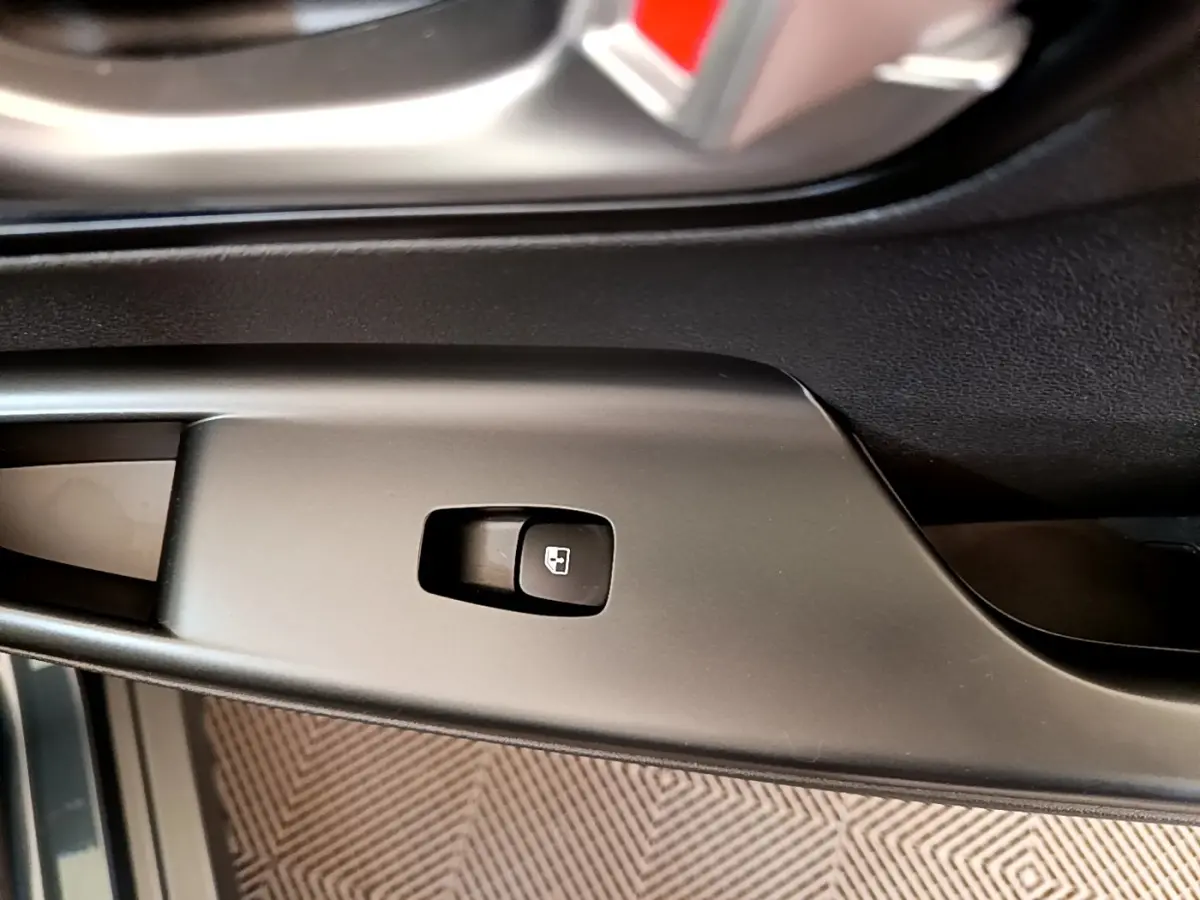 Gros plan sur le bouton de verrouillage des portes côté conducteur dans l'habitacle noir du Hyundai Kona bleu électrique 2023.