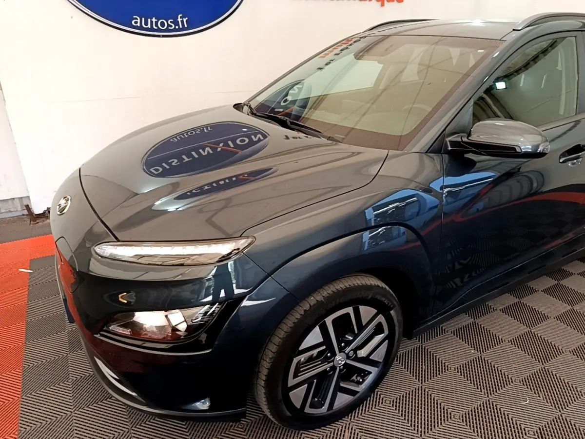 Vue 3/4 avant droit d'une Hyundai Kona électrique bleu foncé avec phares LED et jantes spécifiques.