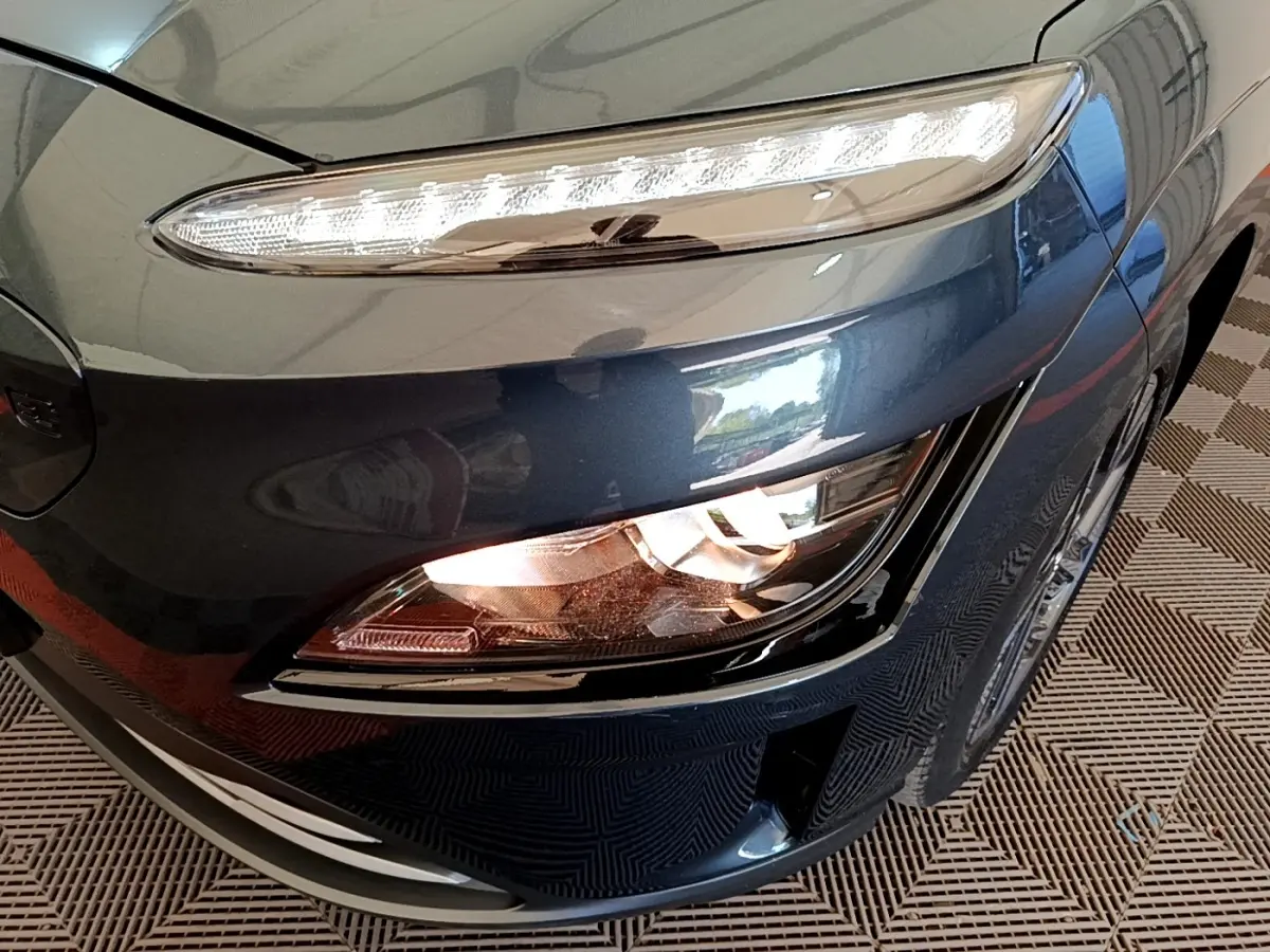 Gros plan sur le phare avant droit bleu électrique d'une Hyundai Kona BEV 64kWh 204ch 2023.