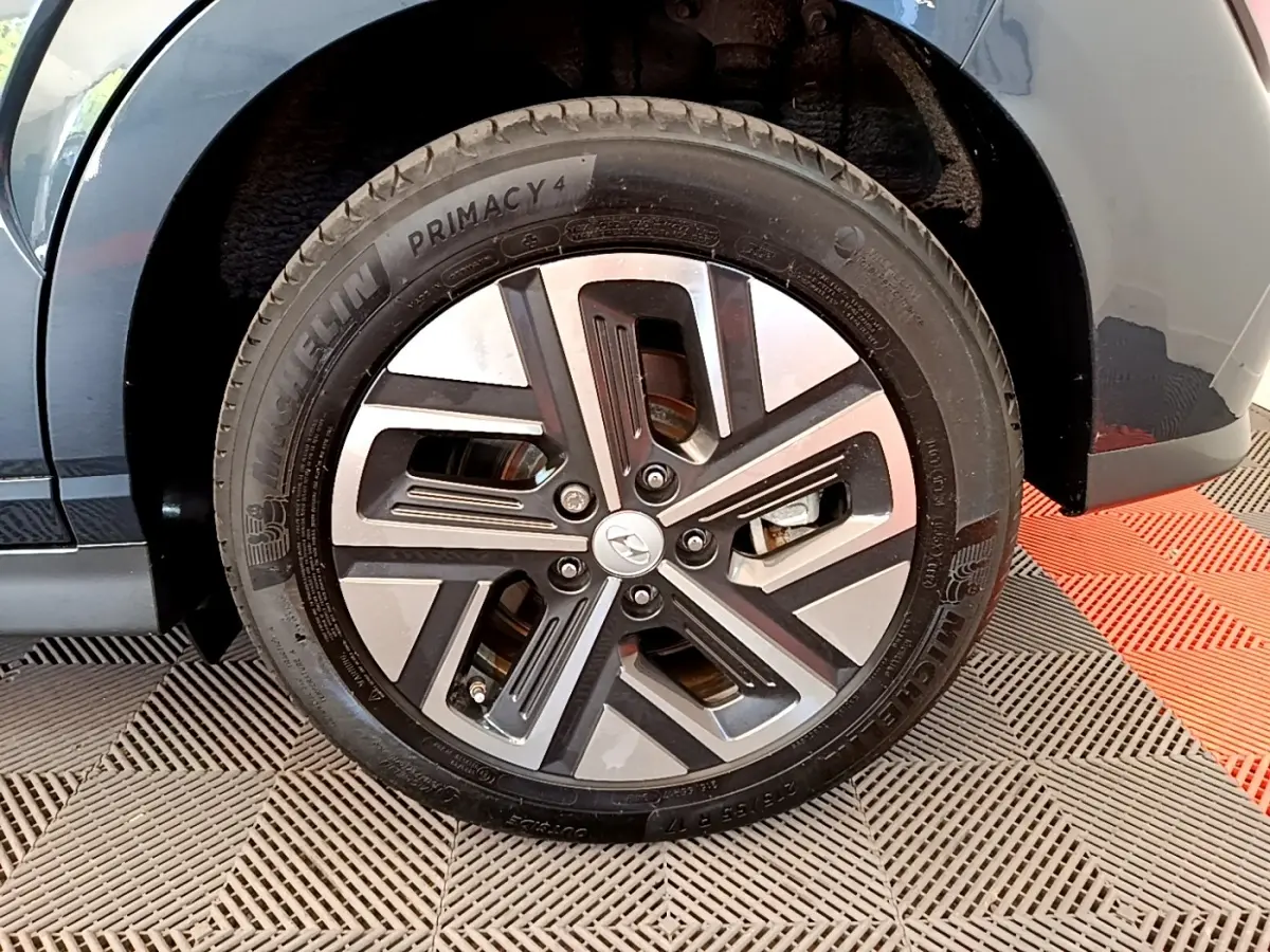 Gros plan sur la roue avant droite d’un Hyundai Kona bleu électrique, avec jante alliage moderne et pneu Michelin.